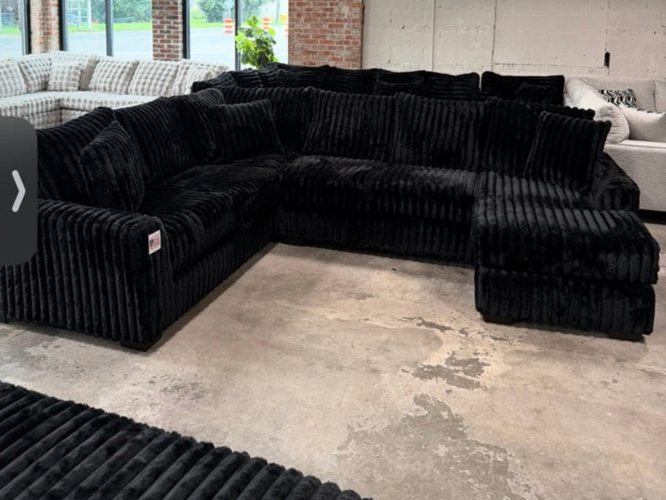 Black plush corduroy U-shaped sectional, showroom view 1