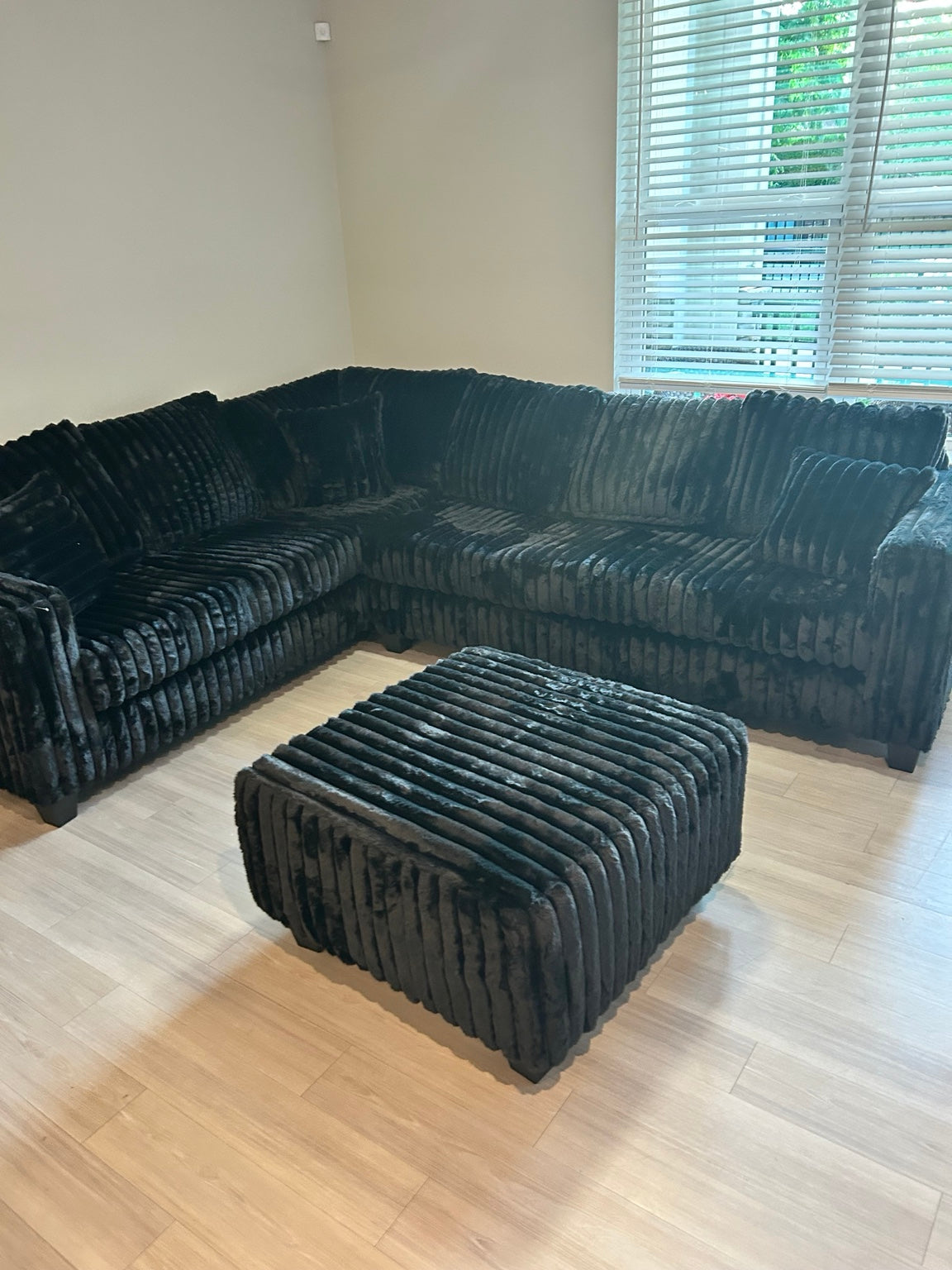 Black plush corduroy sectional with ottoman in home